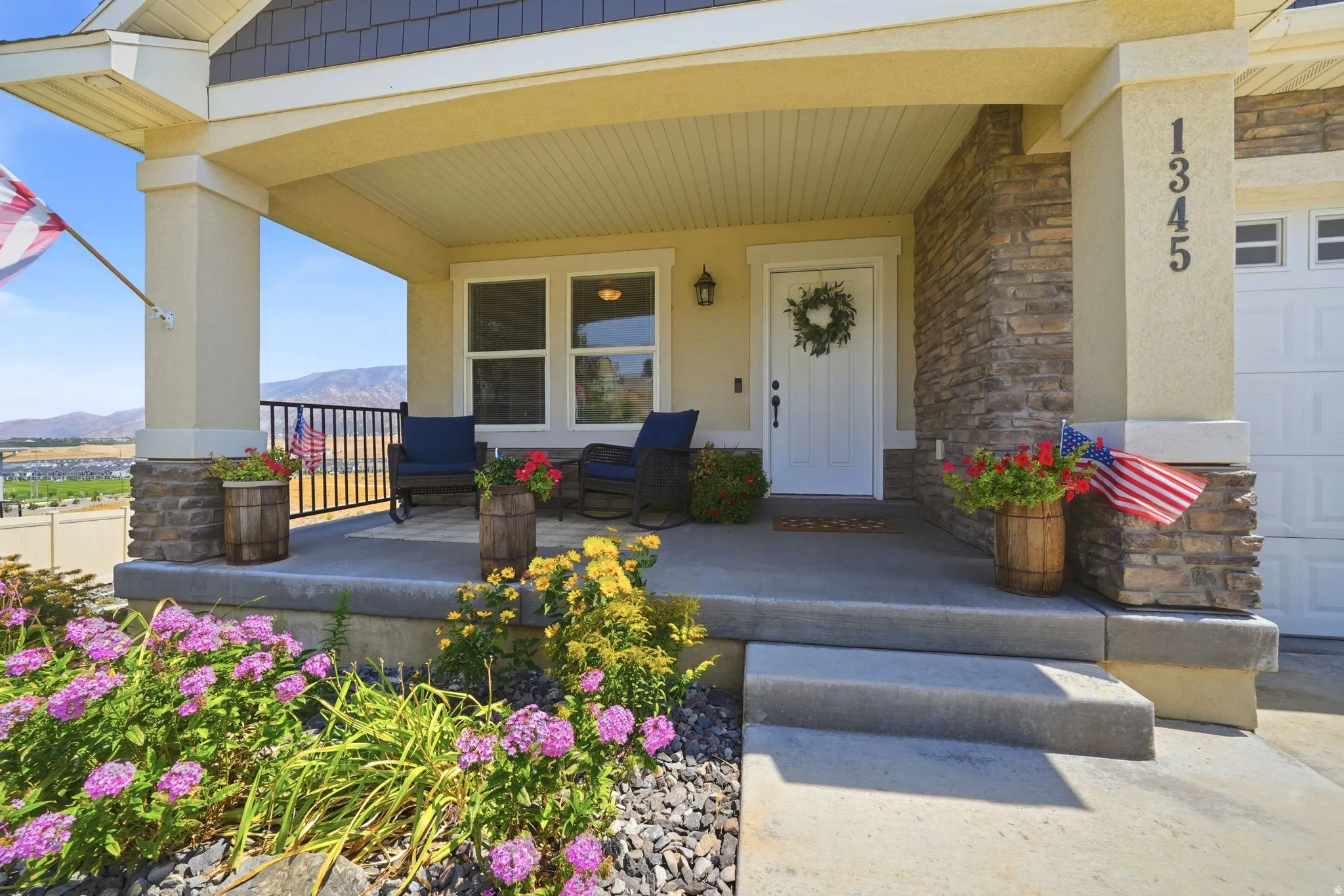 Covered front porch with stone accents, concrete steps, and a white entry door