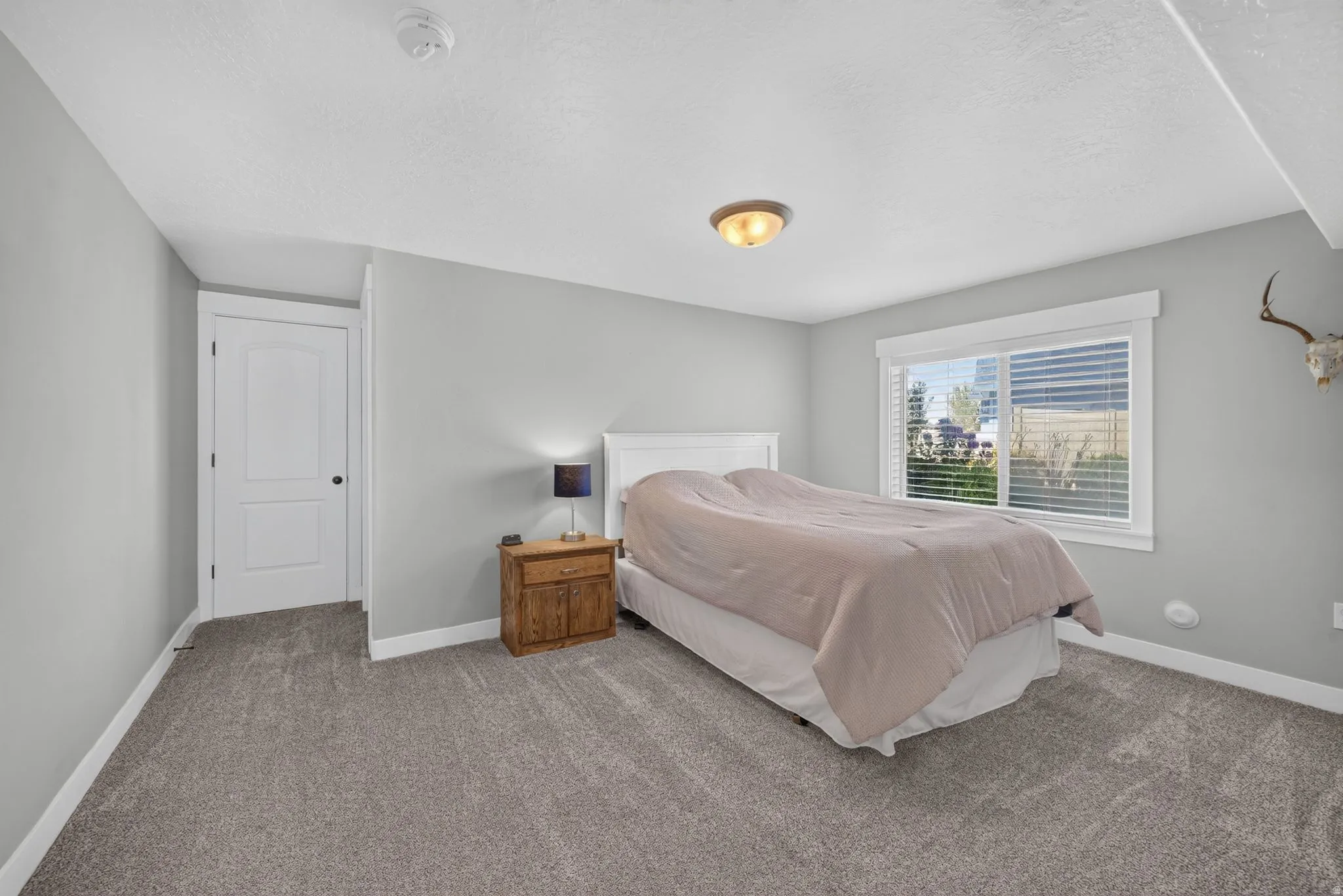 Wall-to-wall carpeting, single window with blinds, recessed lighting, white door with black hardware, and light gray wall paint
