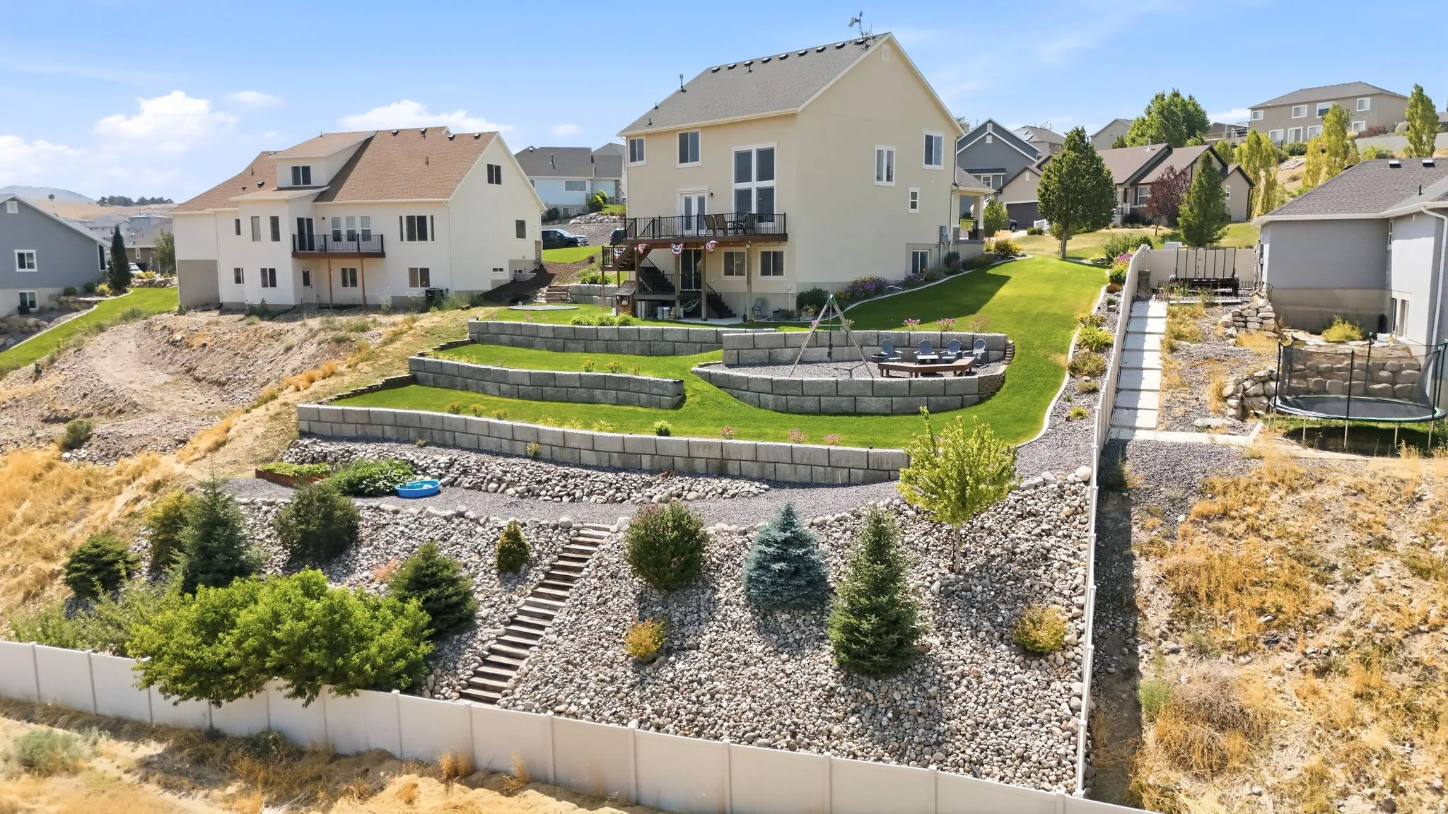Terraced backyard with retaining walls, a manicured lawn, and a stone fire pit