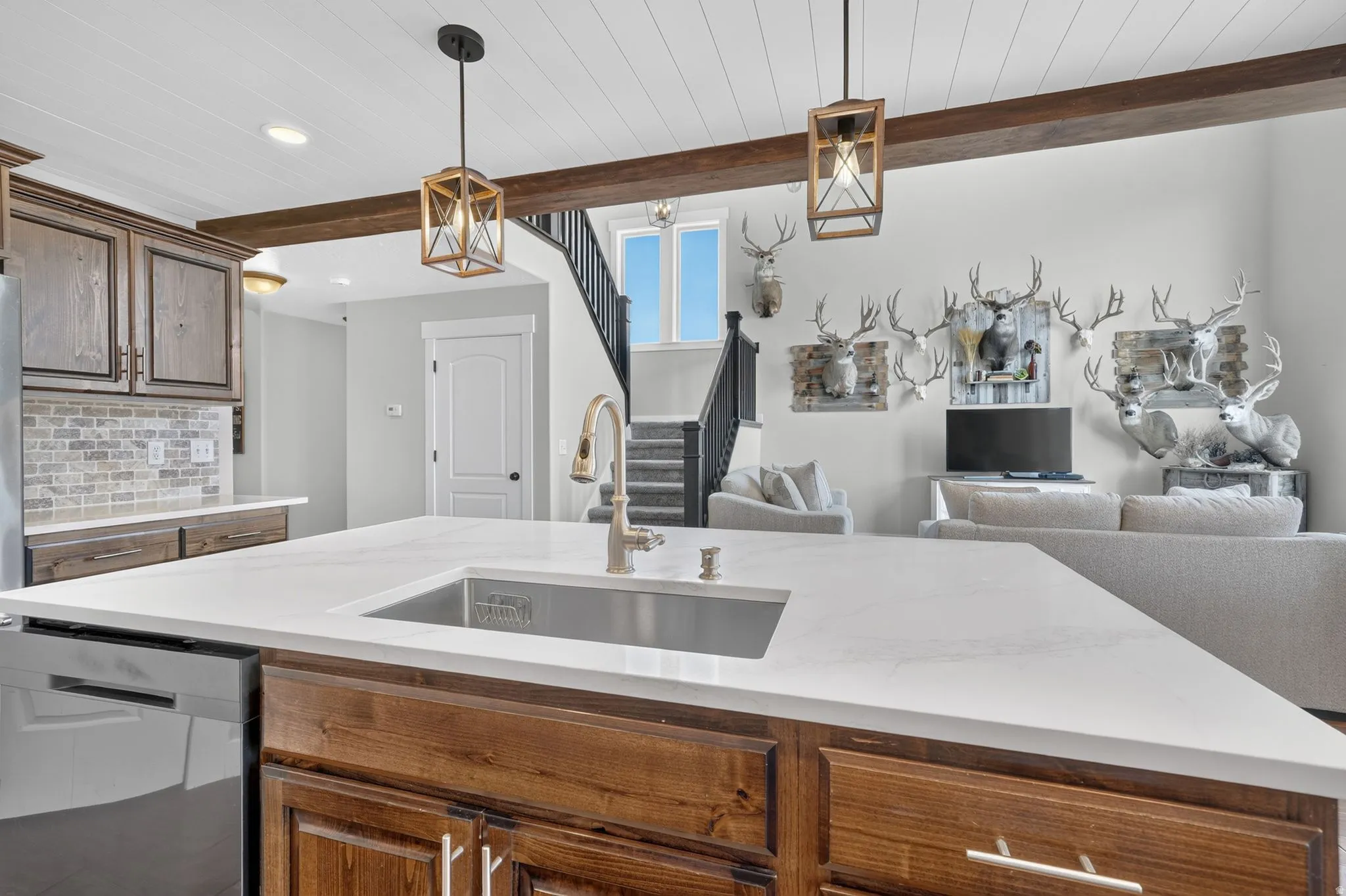 Kitchen island featuring a single-basin undermount sink, a gooseneck faucet, and light-toned countertop