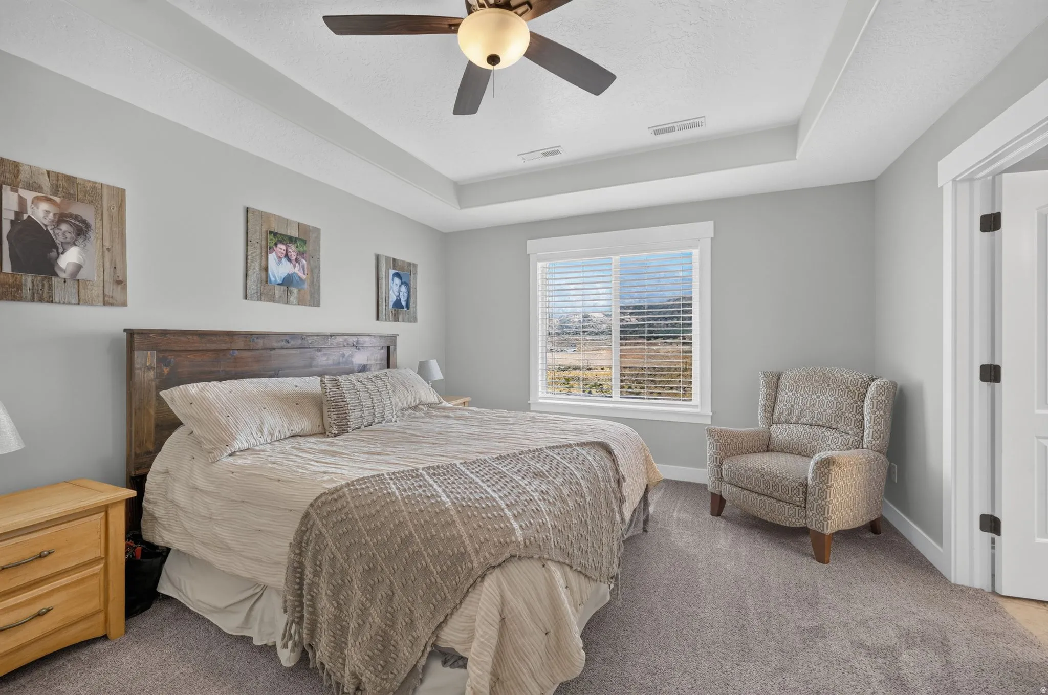Tray ceiling with a ceiling fan, recessed window, and light gray wall paint