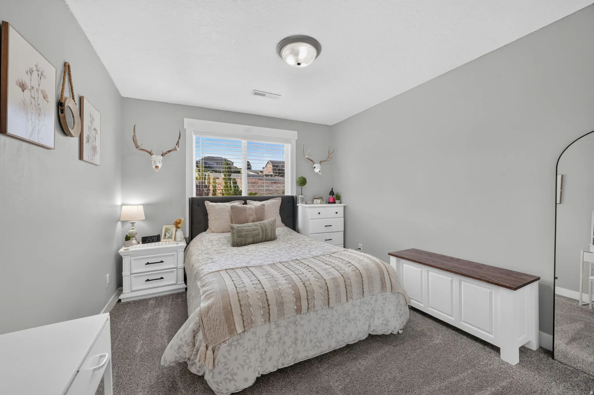 Carpeted bedroom with a window, white window trim, and a ceiling-mounted light fixture