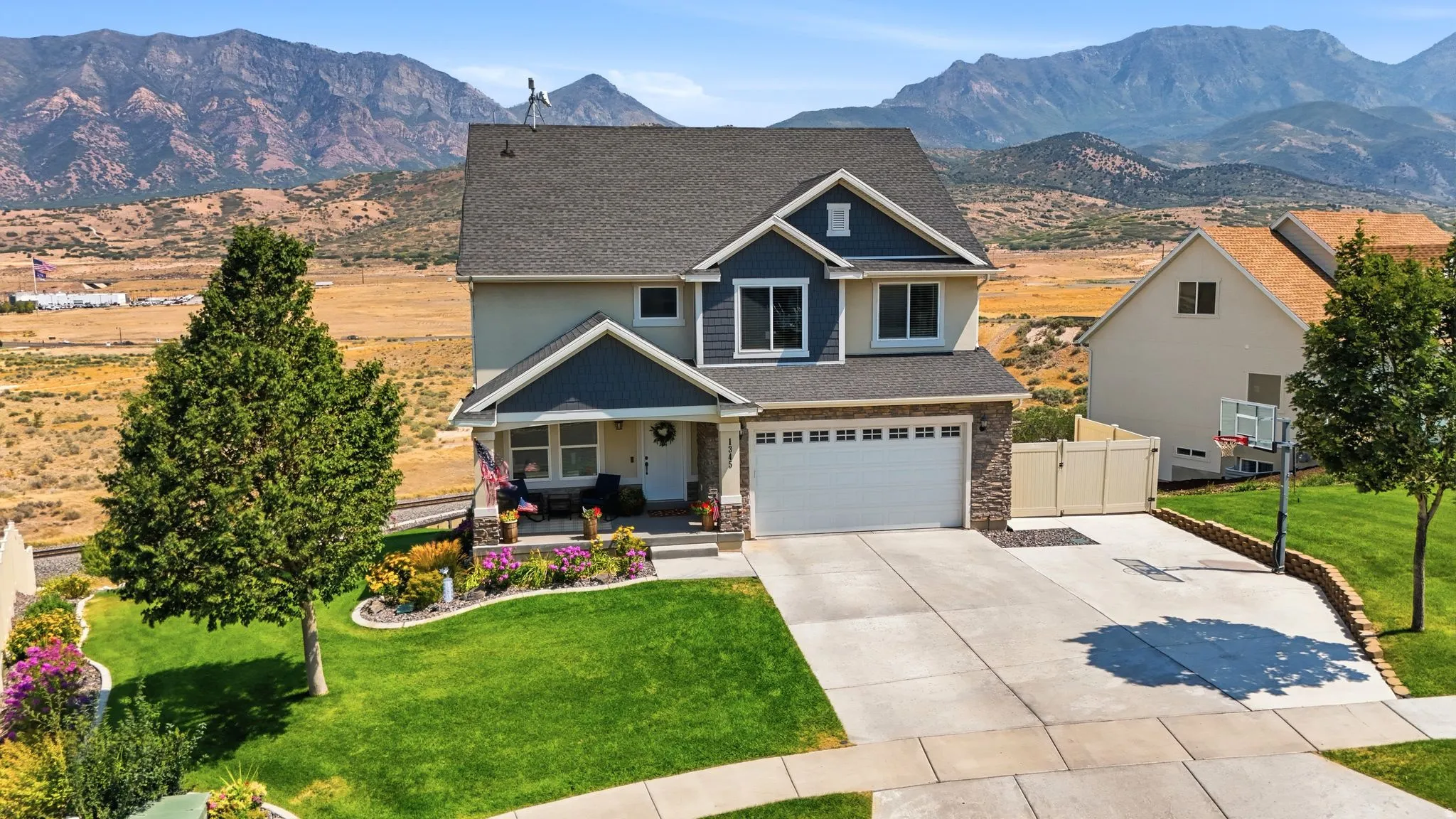 Two-story residence featuring a covered front porch, an attached two-car garage with a stone facade, and a concrete driveway