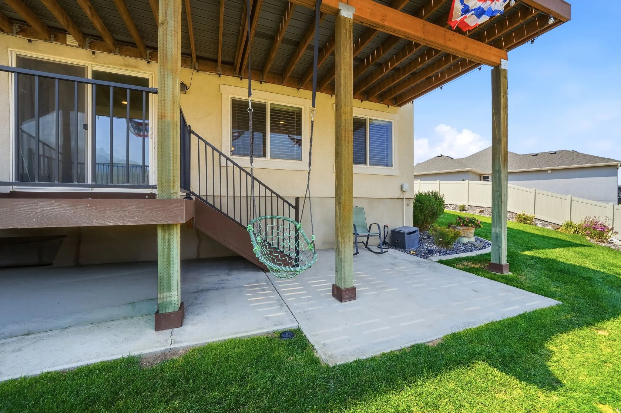 Ground-level patio with concrete slab, exterior siding, and a wooden deck overhead