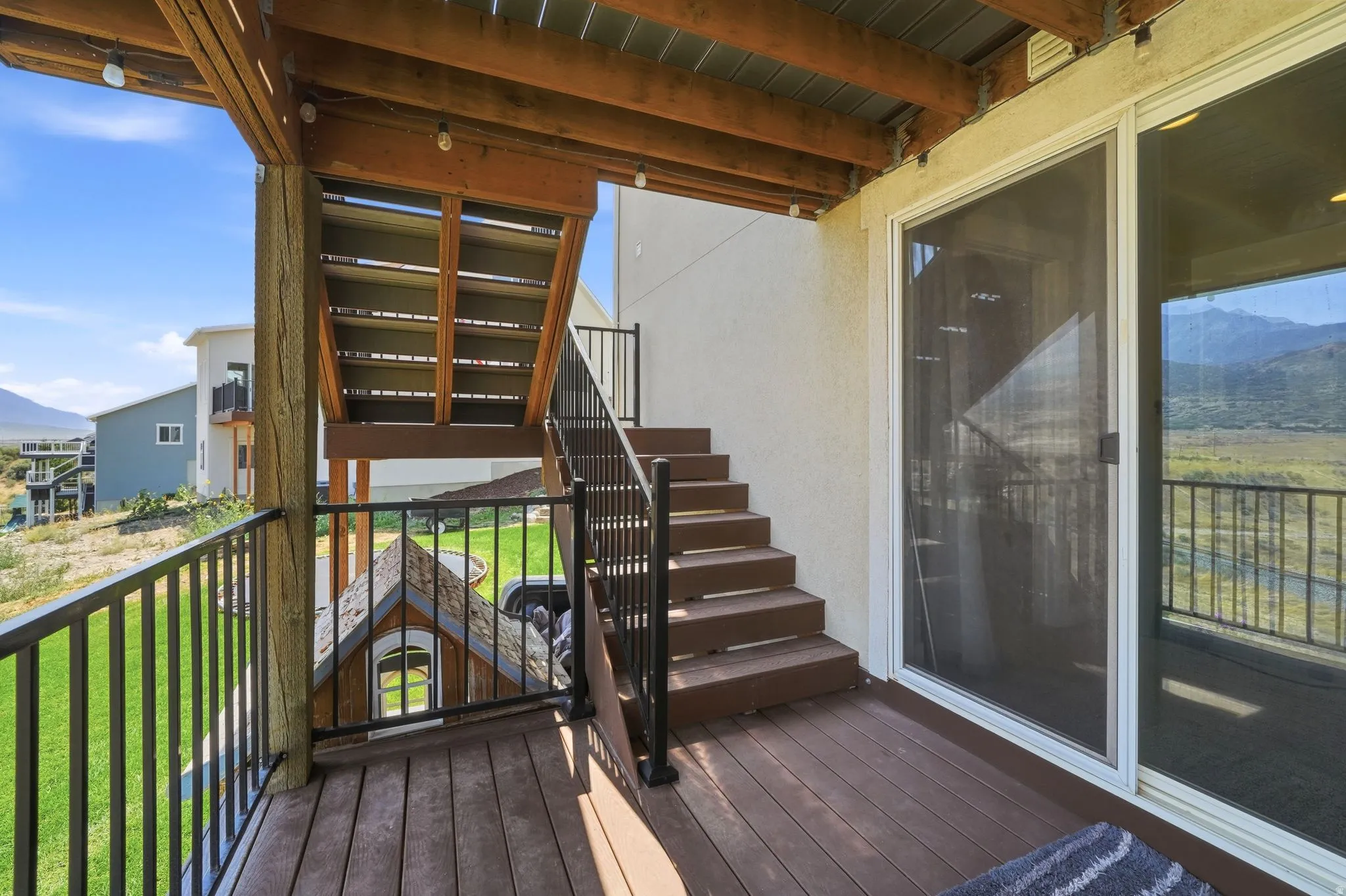 Outdoor deck with wood-finish flooring, black metal railings, and a staircase