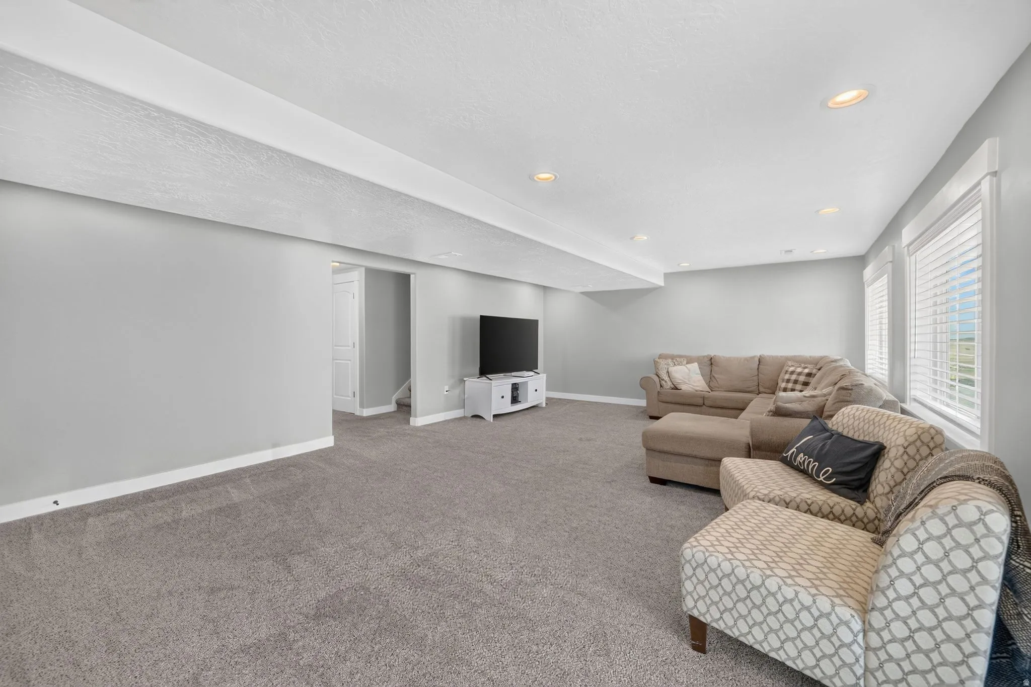 Spacious room featuring gray carpet flooring, recessed lighting, and white trim