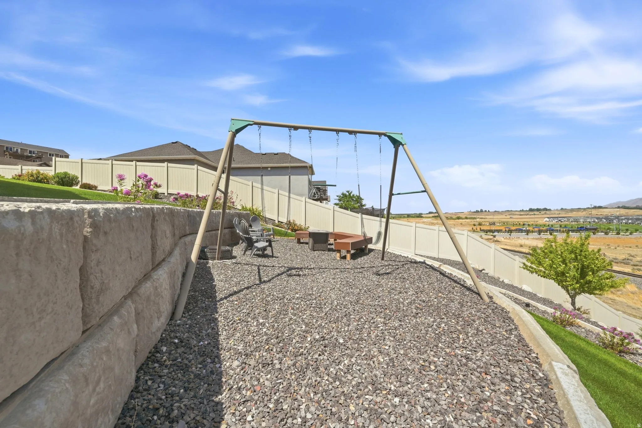 Terraced landscaping with a large retaining wall, gravel ground cover, and a swing set
