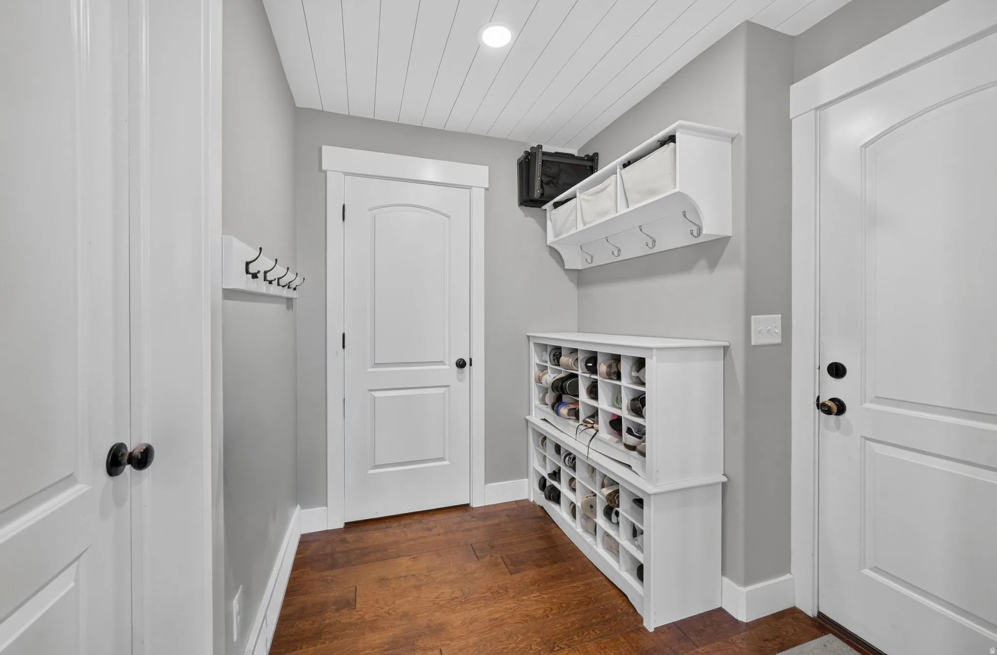 Hardwood-style flooring with white baseboards, a built-in shoe rack, and a wall-mounted coat rack