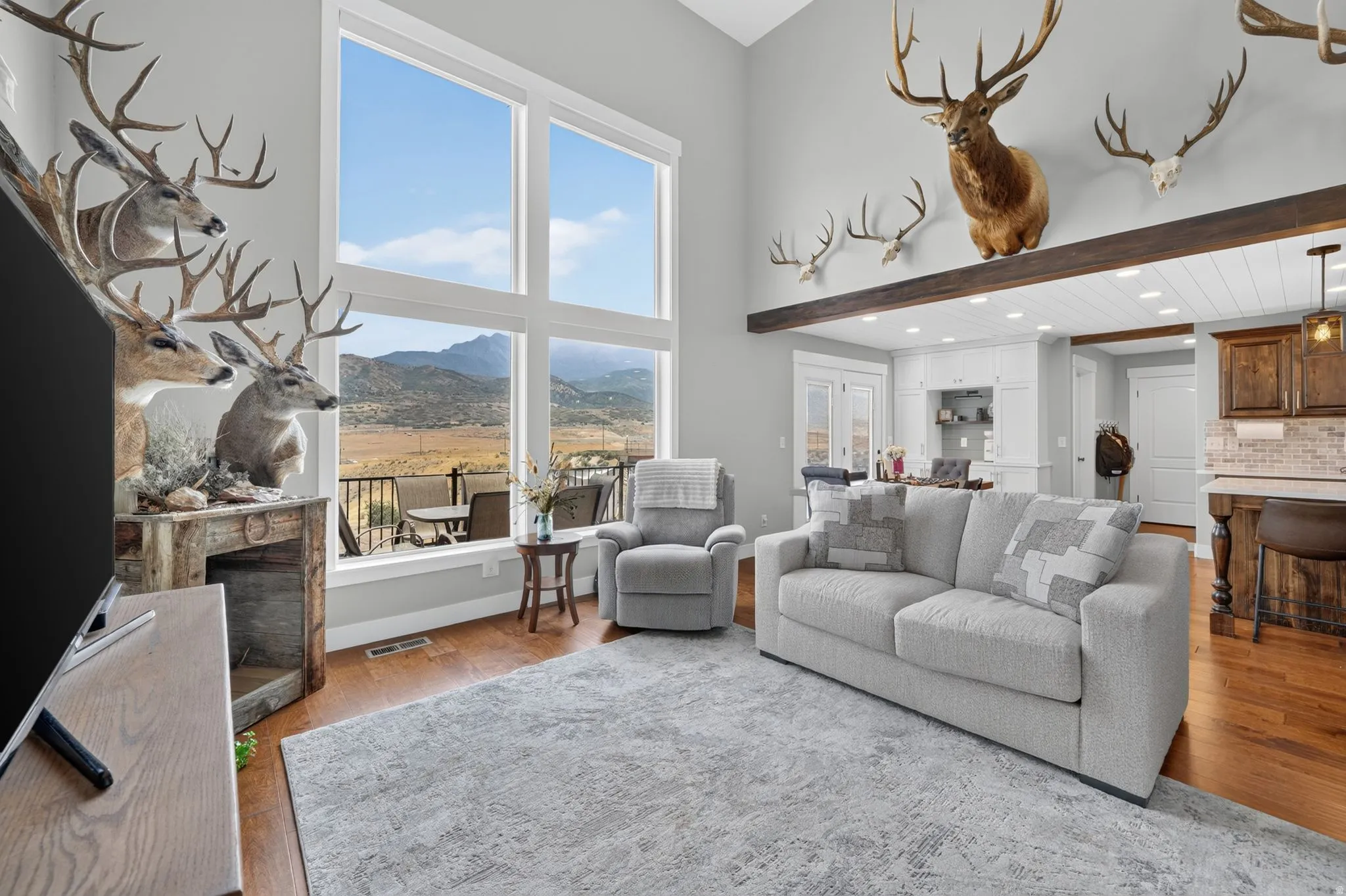 Vaulted ceilings with an exposed wood beam, large picture windows, wood-finish flooring, and recessed lighting