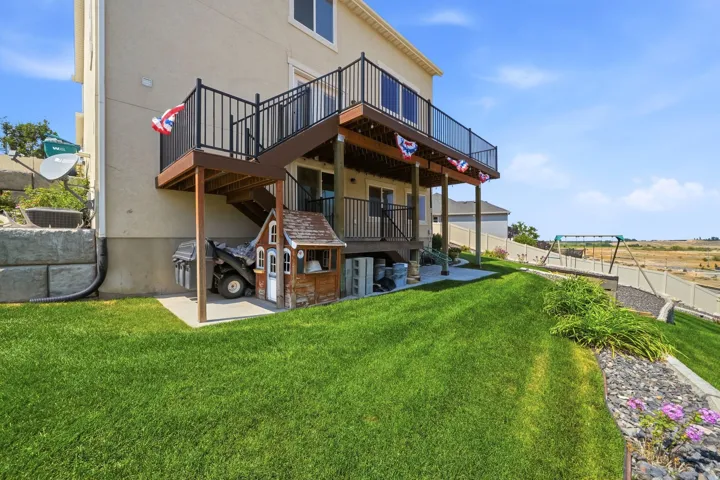 Two-story exterior with a ground-level patio and a raised deck with dark railings