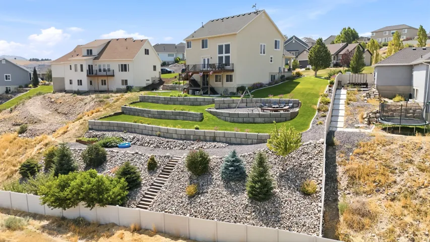 Terraced backyard with retaining walls, a manicured lawn, and a stone fire pit