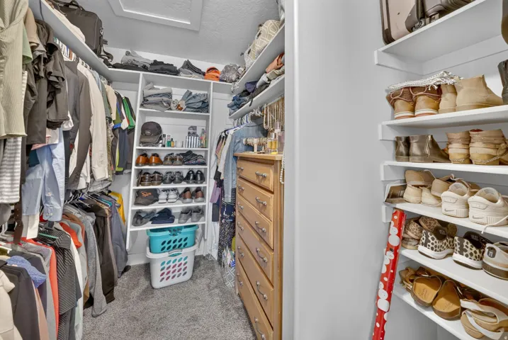 Recessed lighting, built-in shelving, wood-finish dresser with metal hardware, carpet flooring, and white walls