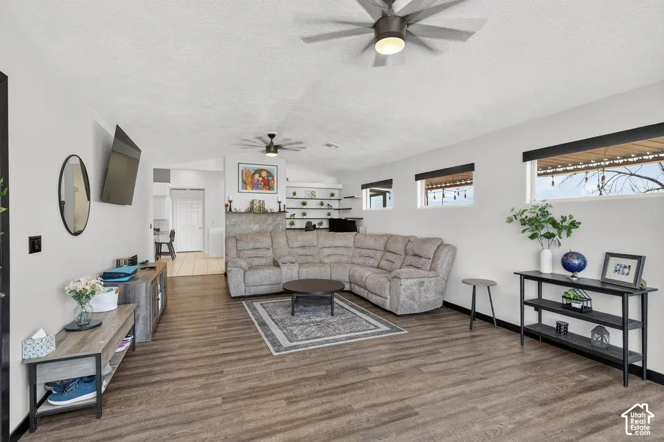 Spacious living area featuring wood-finish flooring, high ceilings, and multiple windows for natural light