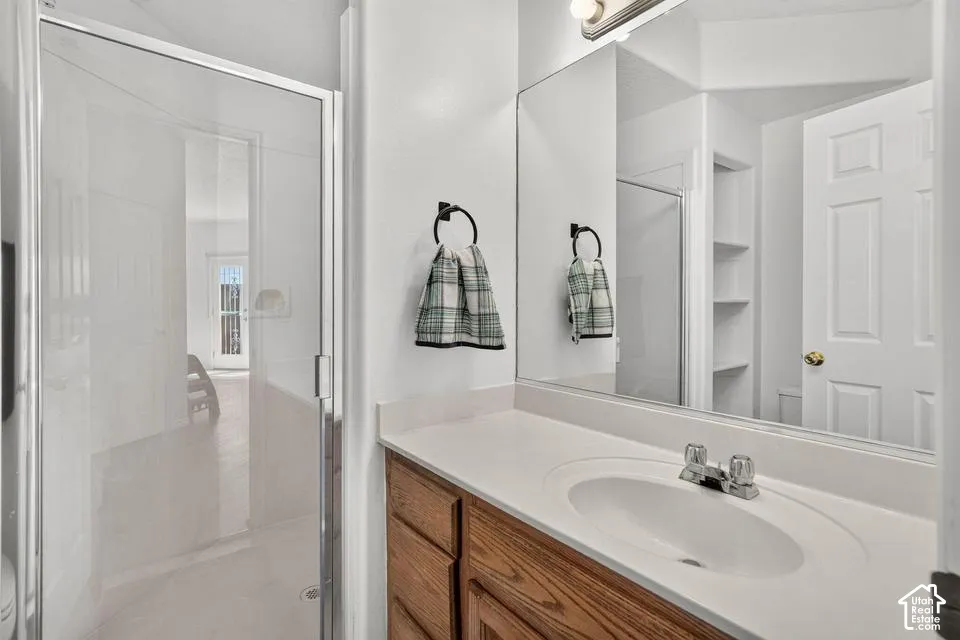 Vanity with wood-finish cabinetry, integrated sink, and chrome-finish fixtures