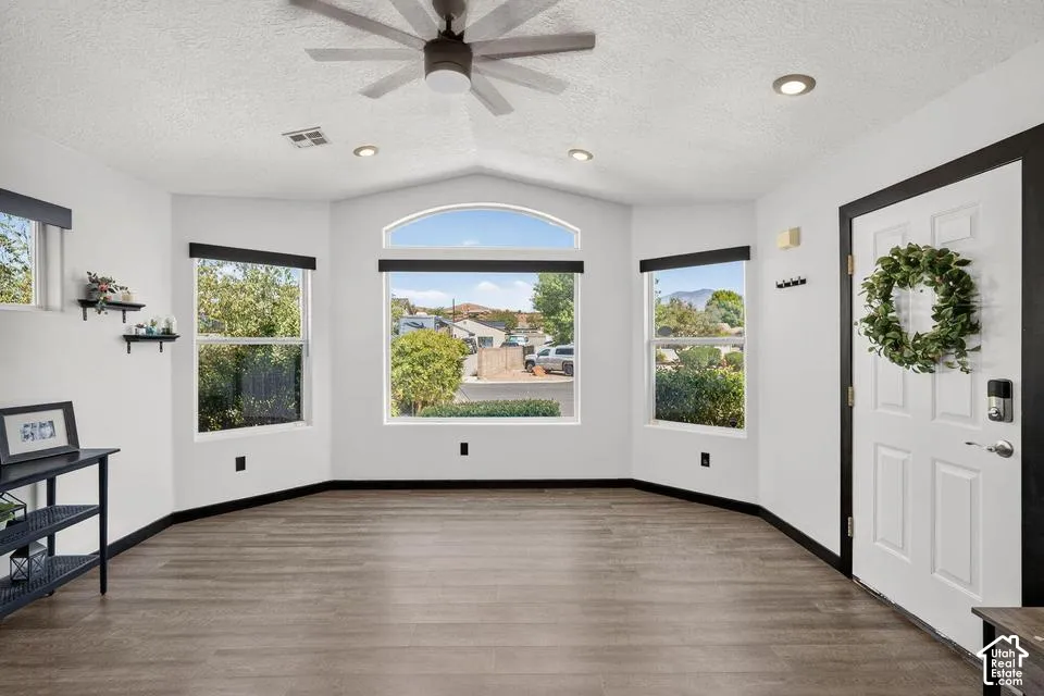 Vaulted ceiling, recessed lighting, ceiling fan, wood-finish flooring, and multiple windows