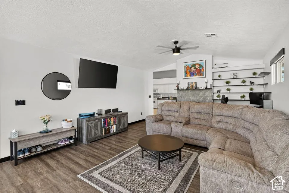 Vaulted ceiling with a ceiling fan, wood-finish flooring, and built-in wall shelving