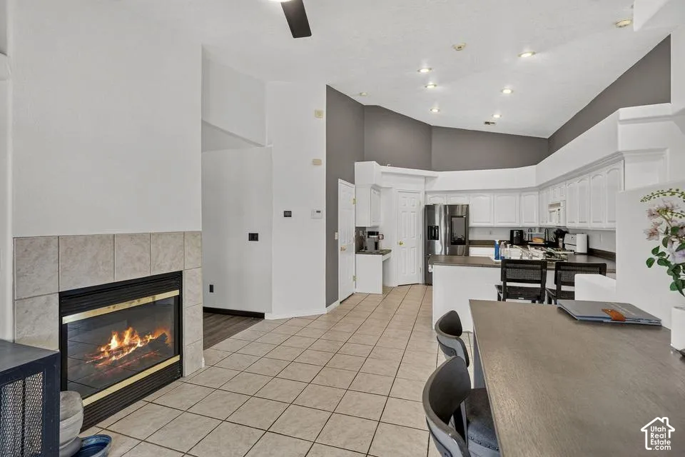 Tile flooring, fireplace with tile surround, vaulted ceiling, recessed lighting, and white cabinetry