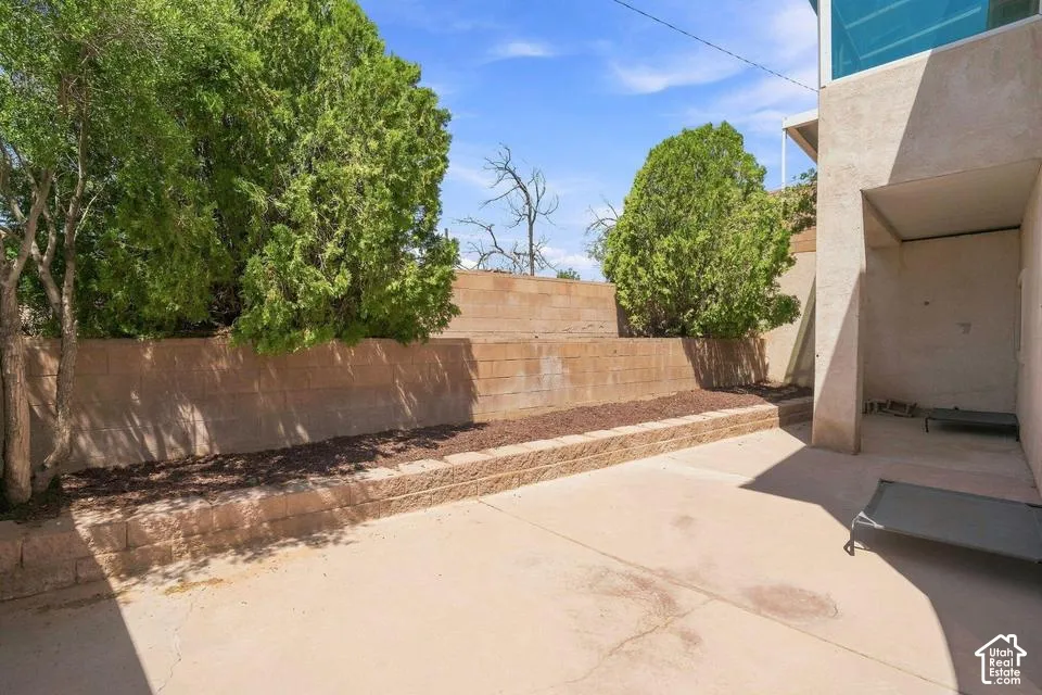 Paved exterior area featuring tiered retaining walls, established plantings, and a sheltered alcove