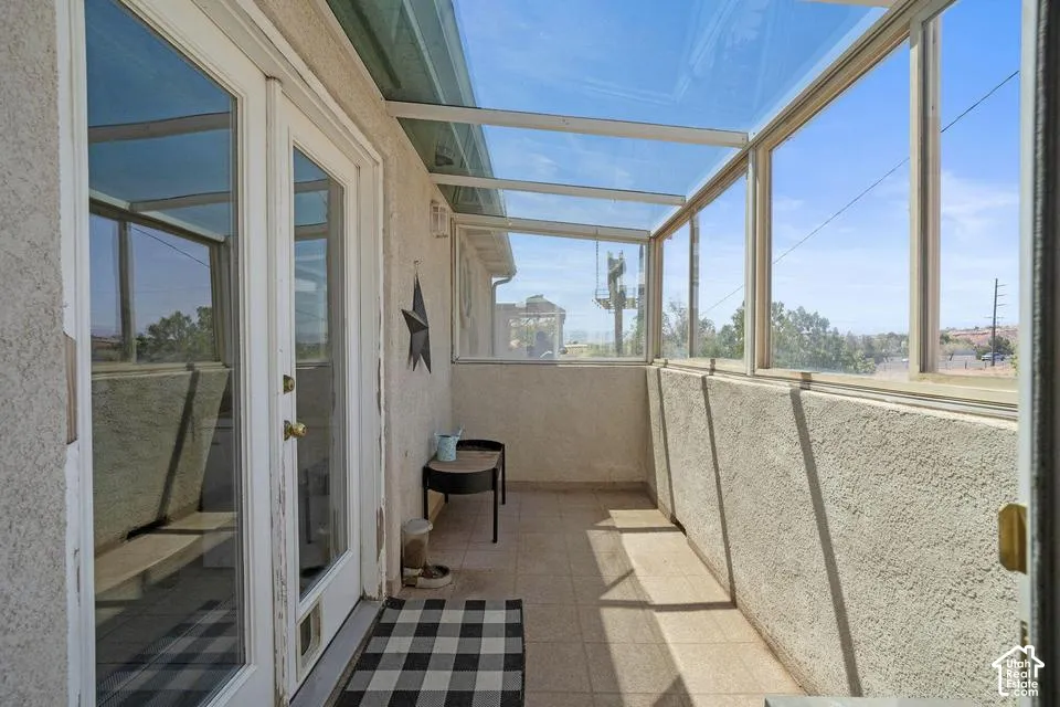 Enclosed patio with full-light French doors, glass roof, and tiled flooring