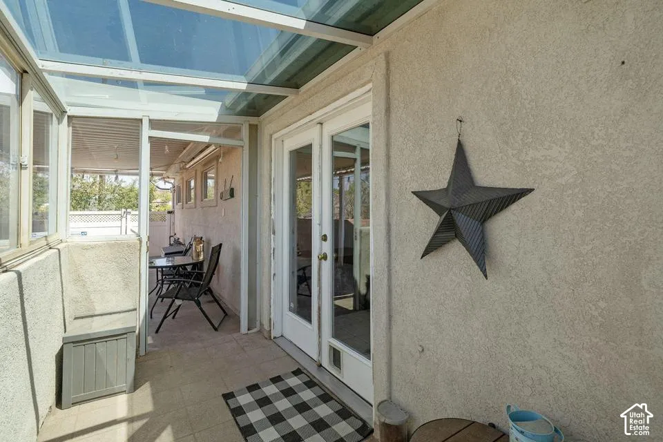 Enclosed patio featuring a clear panel roof, stucco exterior, ceramic tile flooring, and a double-pane glass door
