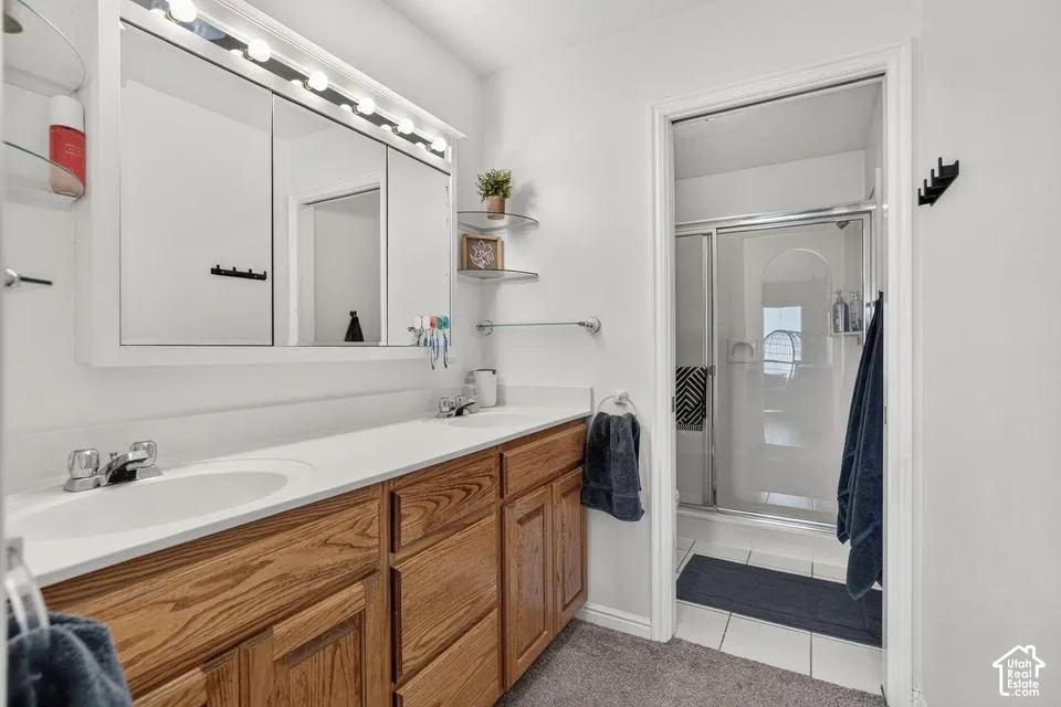 Double vanity with white sinks, wood-finish cabinetry, and white countertops