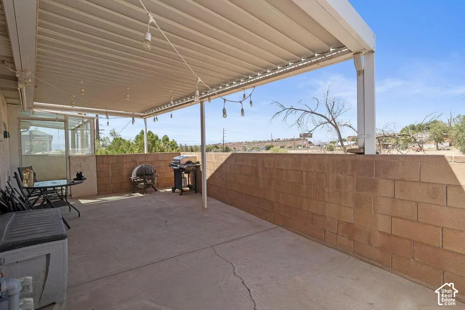 Concrete patio with a full-length overhead shade structure and an opaque knee wall