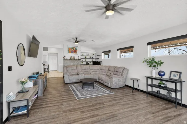 Spacious living area featuring wood-finish flooring, high ceilings, and multiple windows for natural light