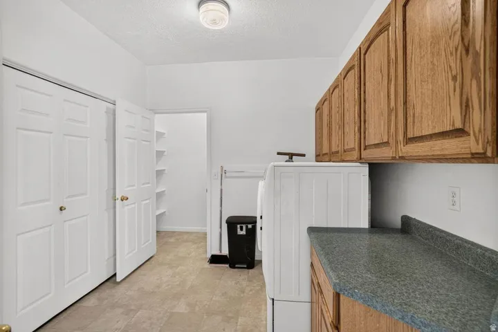 Wood-finish cabinetry with a laminate countertop, featuring a built-in closet with bi-fold doors, recessed shelving, and a ceiling-mounted light fixture