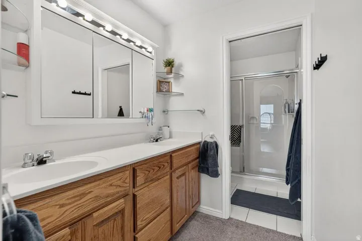 Double vanity with white sinks, wood-finish cabinetry, and white countertops