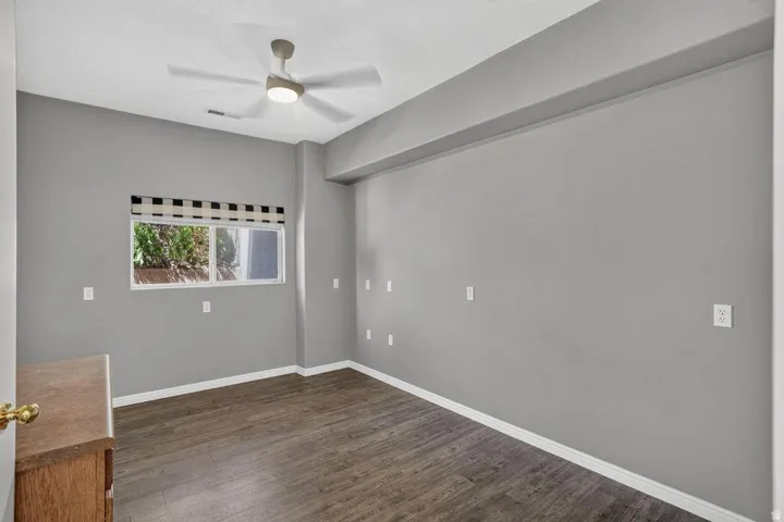 Wood-finish flooring, recessed window, and overhead ceiling fan with integrated lighting