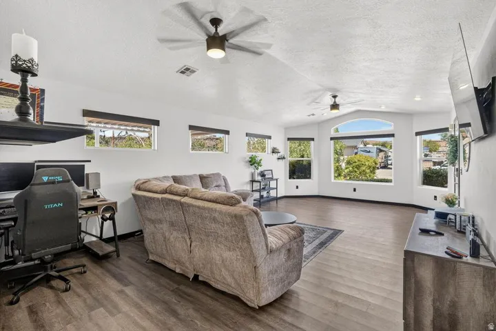 Expansive living area with wood-finish flooring, vaulted ceilings, and multiple windows