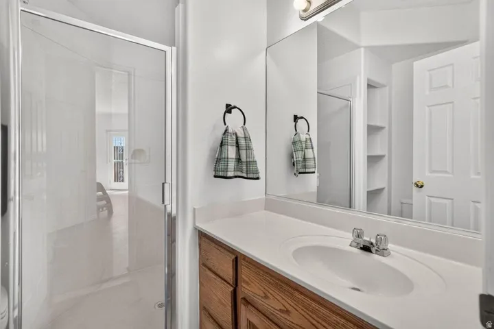 Vanity with wood-finish cabinetry, integrated sink, and chrome-finish fixtures