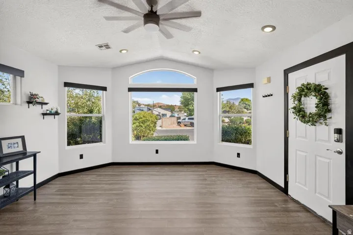 Vaulted ceiling, recessed lighting, ceiling fan, wood-finish flooring, and multiple windows