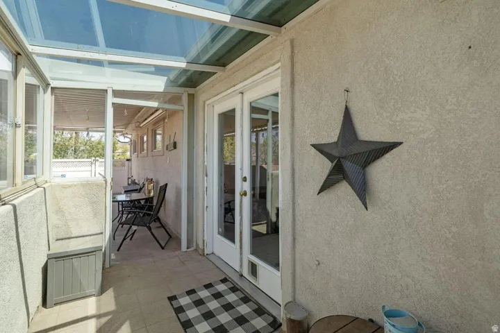 Enclosed patio featuring a clear panel roof, stucco exterior, ceramic tile flooring, and a double-pane glass door