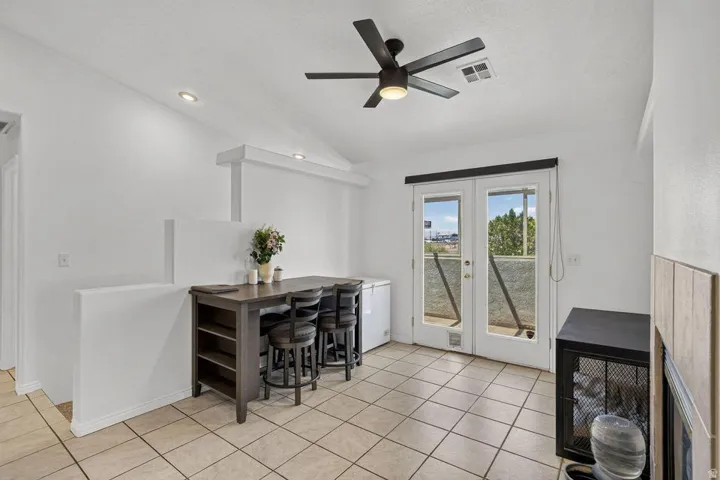 Vaulted ceiling with a ceiling fan, recessed lighting, tile flooring, and double French doors