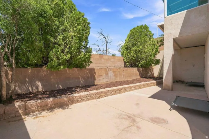 Paved exterior area featuring tiered retaining walls, established plantings, and a sheltered alcove