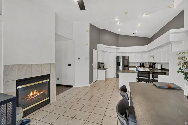 Tile flooring, fireplace with tile surround, vaulted ceiling, recessed lighting, and white cabinetry