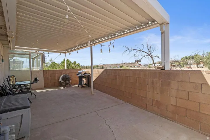 Concrete patio with a full-length overhead shade structure and an opaque knee wall