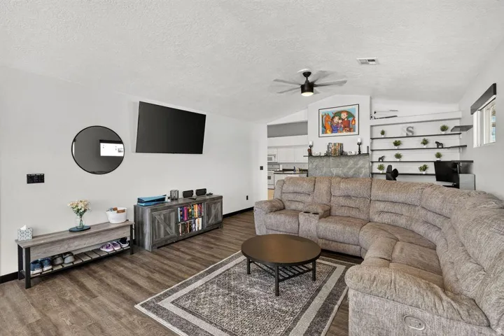 Vaulted ceiling with a ceiling fan, wood-finish flooring, and built-in wall shelving