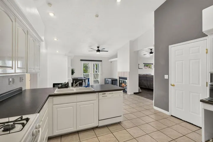 Kitchen featuring white cabinetry, dark countertops, a dual-basin sink, and tile flooring