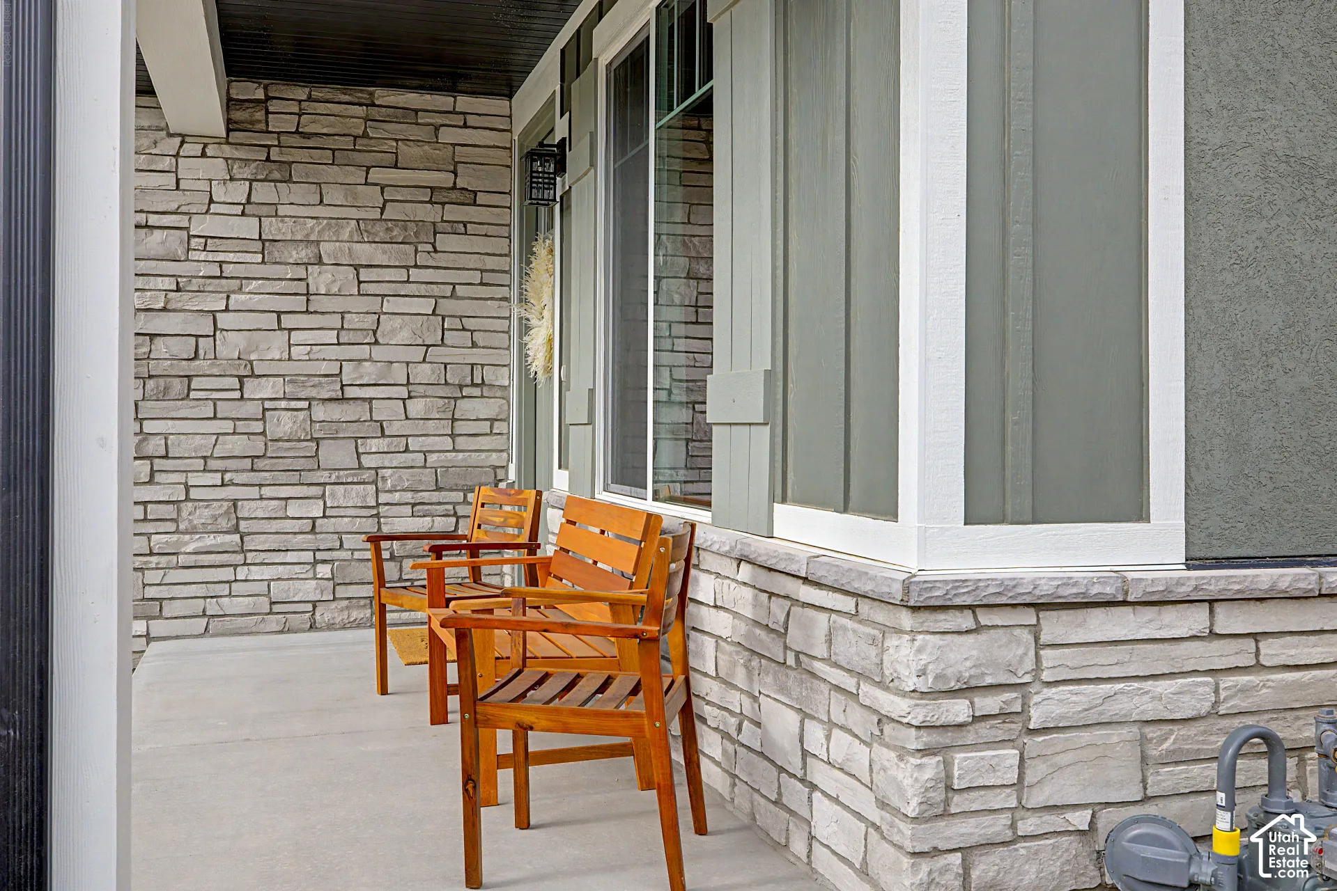Exterior stone veneer, concrete porch, and vertical siding