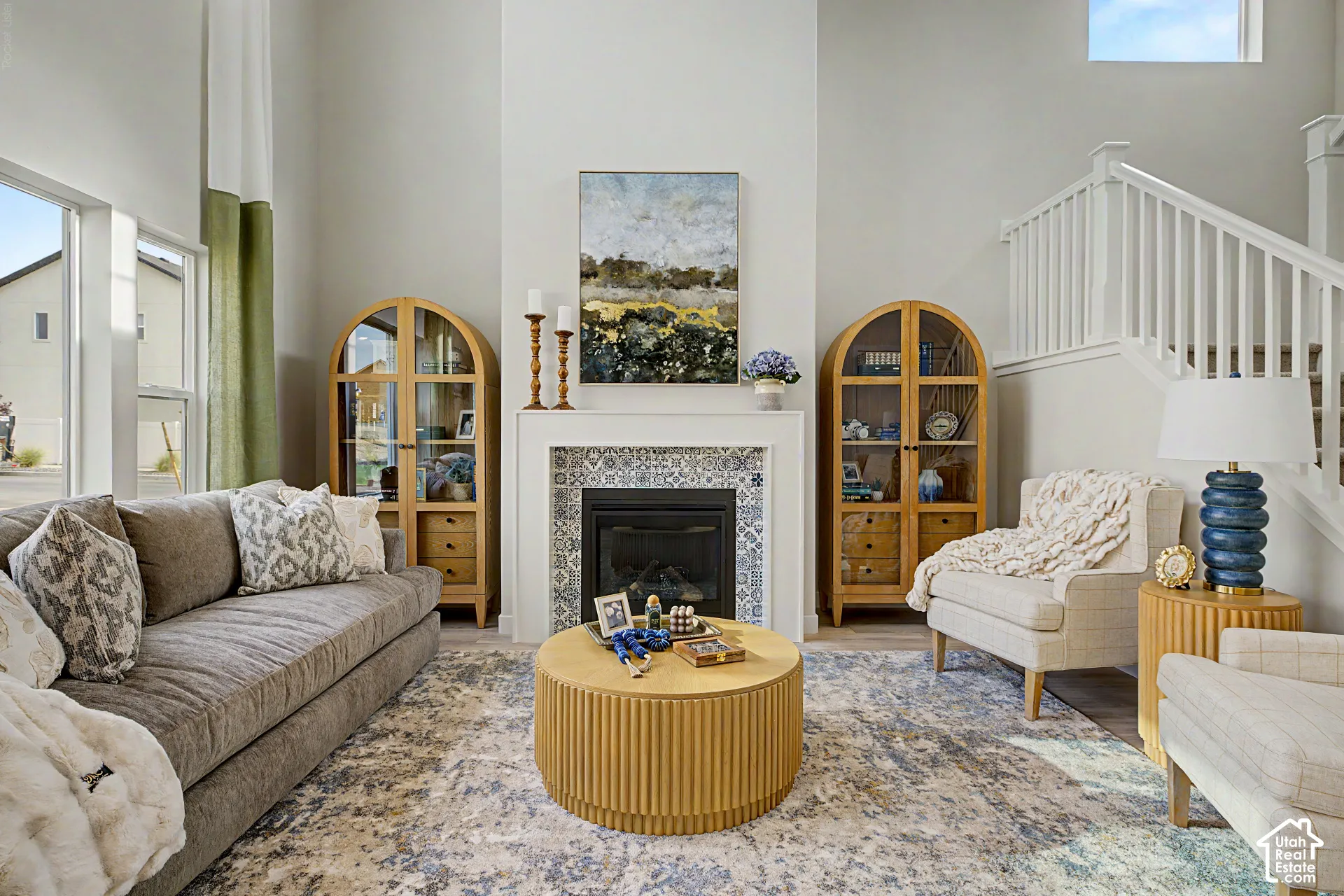 Spacious living area featuring high ceilings, a fireplace with decorative tile surround, and large windows