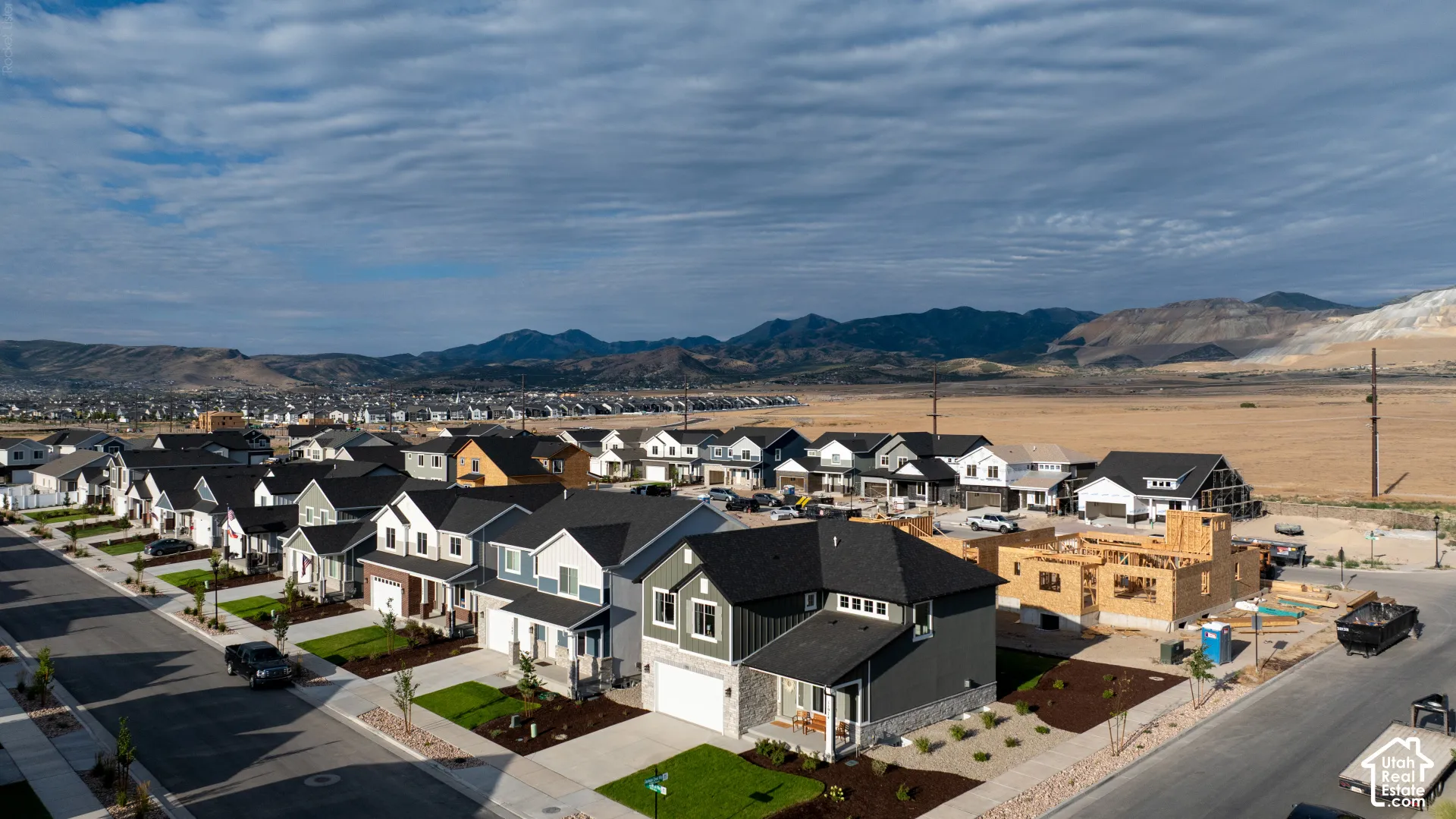 New construction community with varied architectural styles, manicured lawns, and mountain scenery