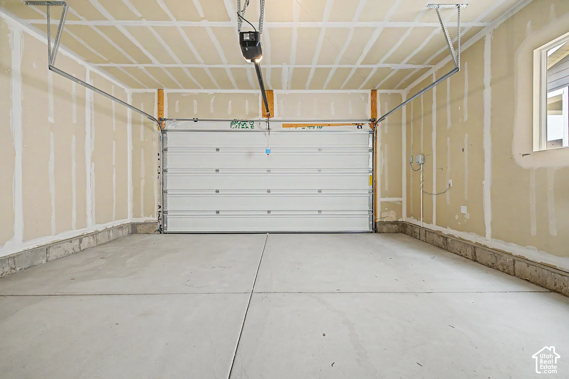 Concrete flooring, automatic garage door opener, perimeter window, exposed ceiling joists, unfinished drywall walls