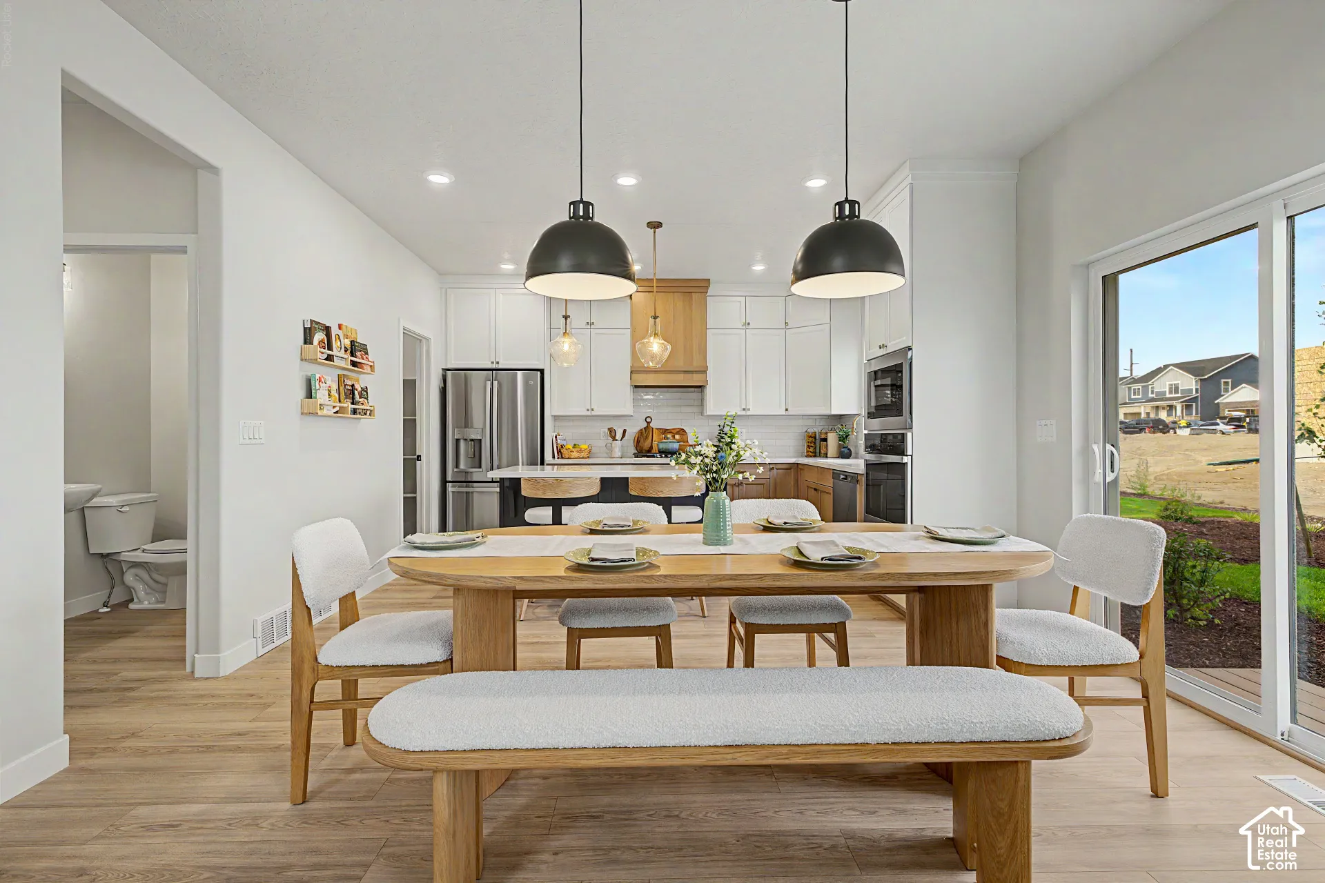 Open-concept dining area with wood-finish flooring, recessed lighting, and a sliding glass door