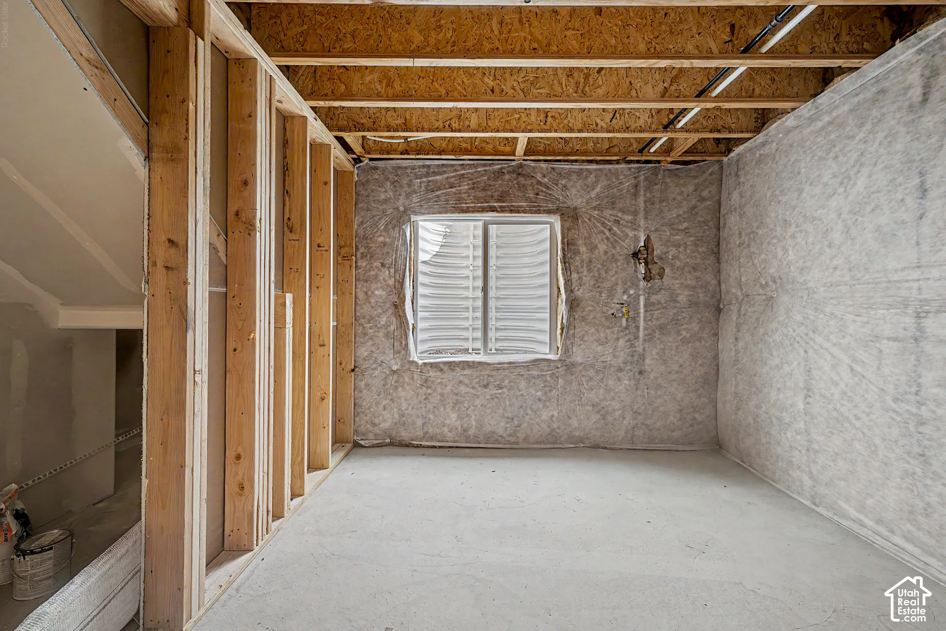 Unfinished room with concrete flooring, wood framing, and a window