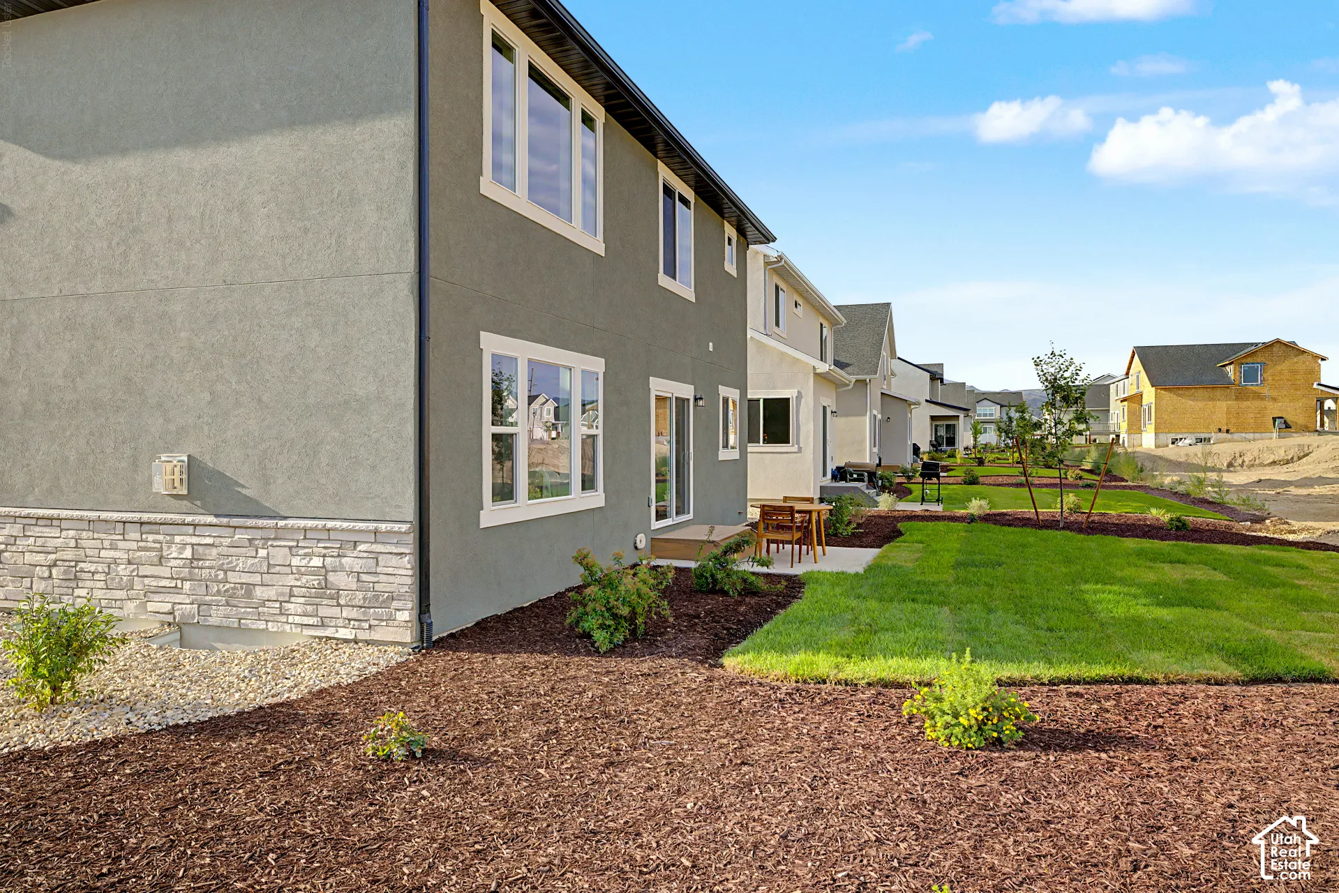 Stucco exterior with a stone veneer accent, sliding glass door, and a ground-level patio