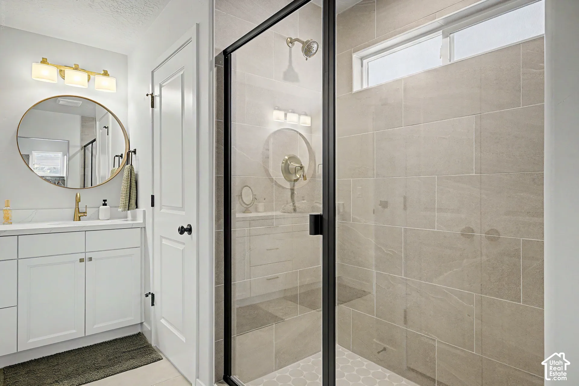 White vanity with quartz countertop, a round mirror, and a three-light fixture