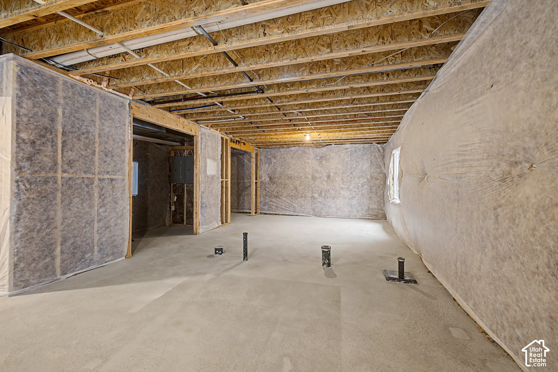 Unfinished basement with exposed ceiling joists, concrete flooring, and roughed-in plumbing