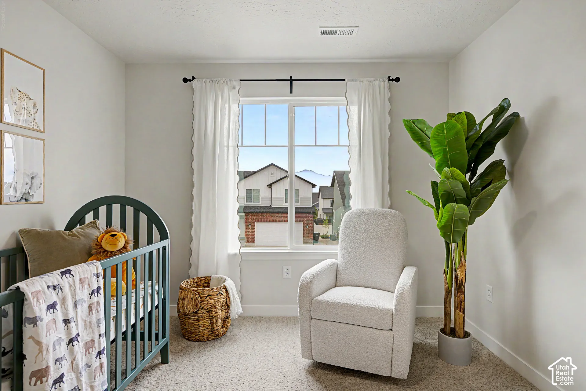 Carpeted interior with light-toned walls, a large window with white trim, and white scalloped curtains